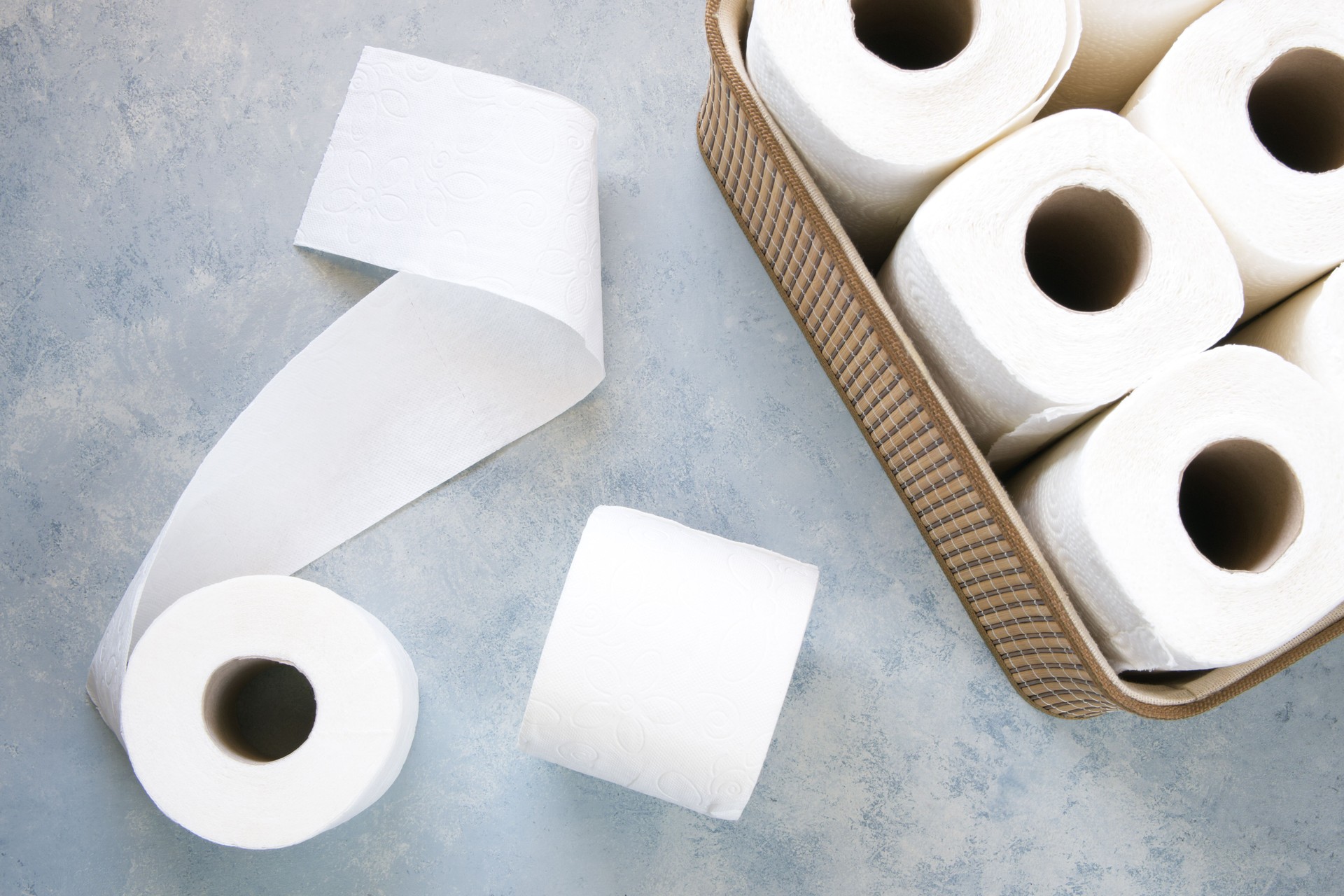 Toilet paper rolls in wicker basket on grey table